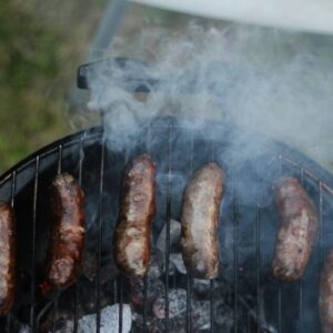 six sausages on black charcoal grill