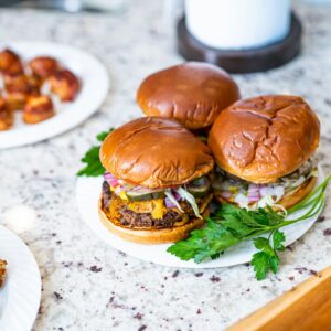 a couple of hamburgers on a plate next to a plate of food